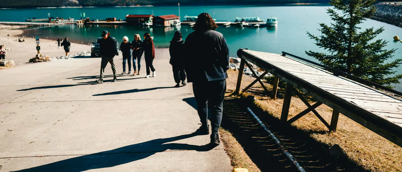 Vier Freunde sitzen von hinten gesehen auf einem Steg am See