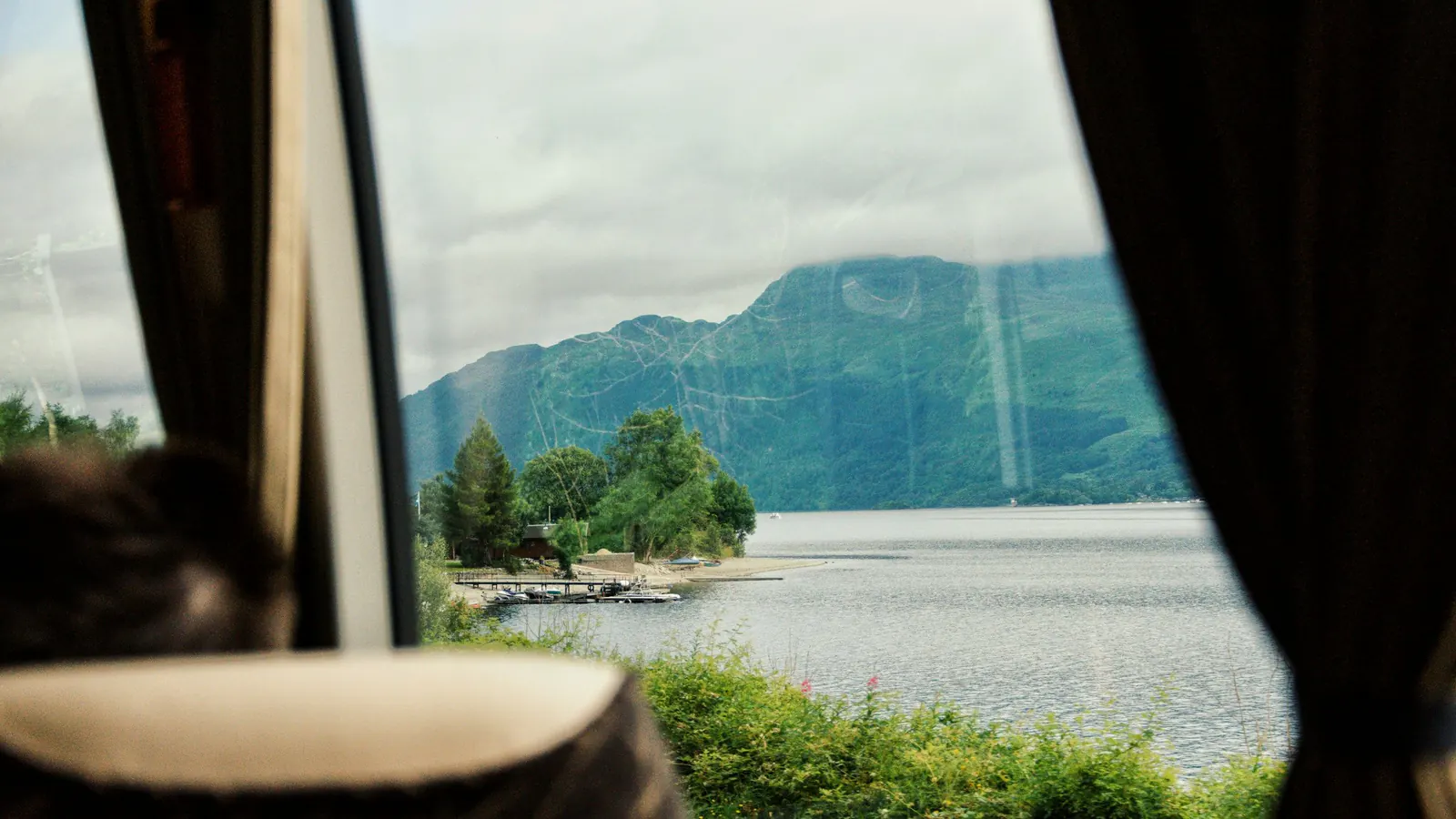 View from a window onto a lake and wooded mountains on a bright day