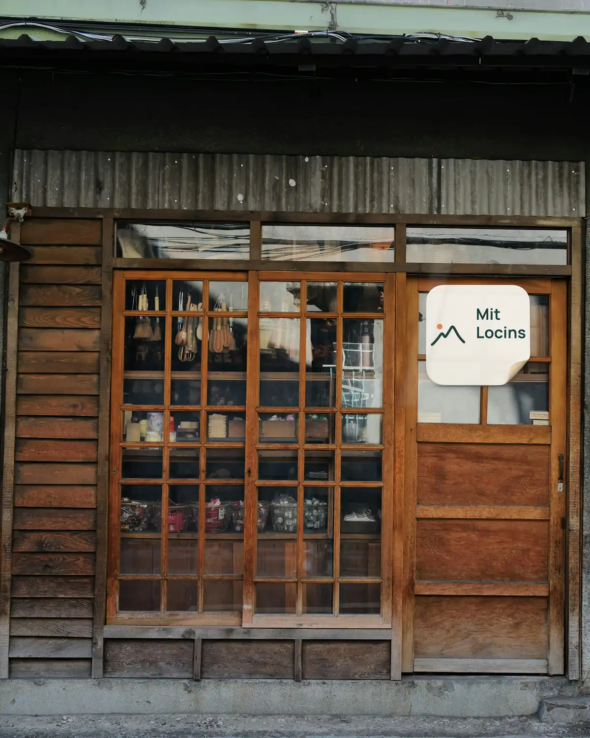 Wooden door of a small shop in an old town, with a “With Locins” sticker on the glass
