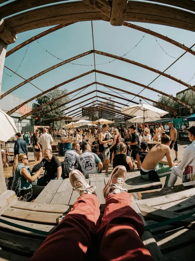 Menschen ruhen sich am Tag unter einem Holzpavillon auf einem Festival aus