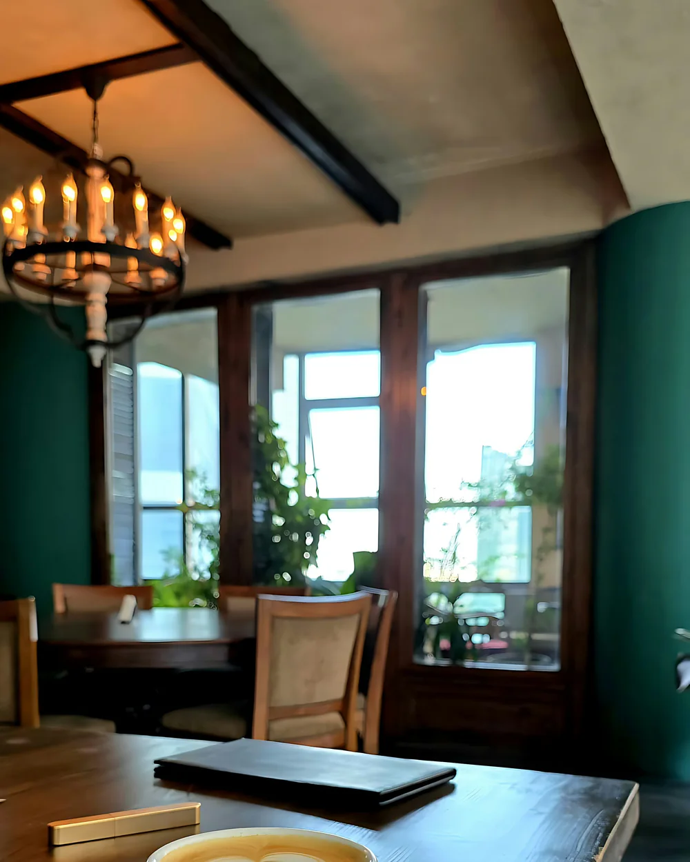 Tisch am Fenster eines kleinen Cafés mit einer Tasse Kaffee im Morgenlicht