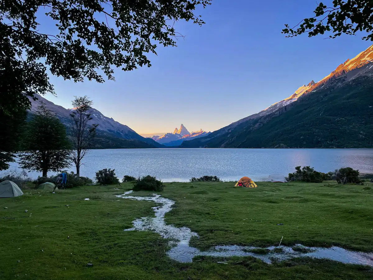 Zelte und Wohnwagen auf einem Campingplatz am Seeufer im Morgenlicht