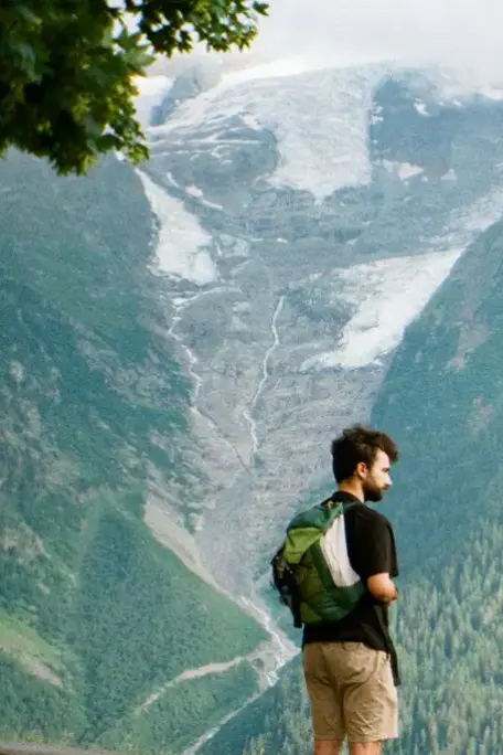 Ein Wanderer steht am Hang und schaut auf einen Gletscher