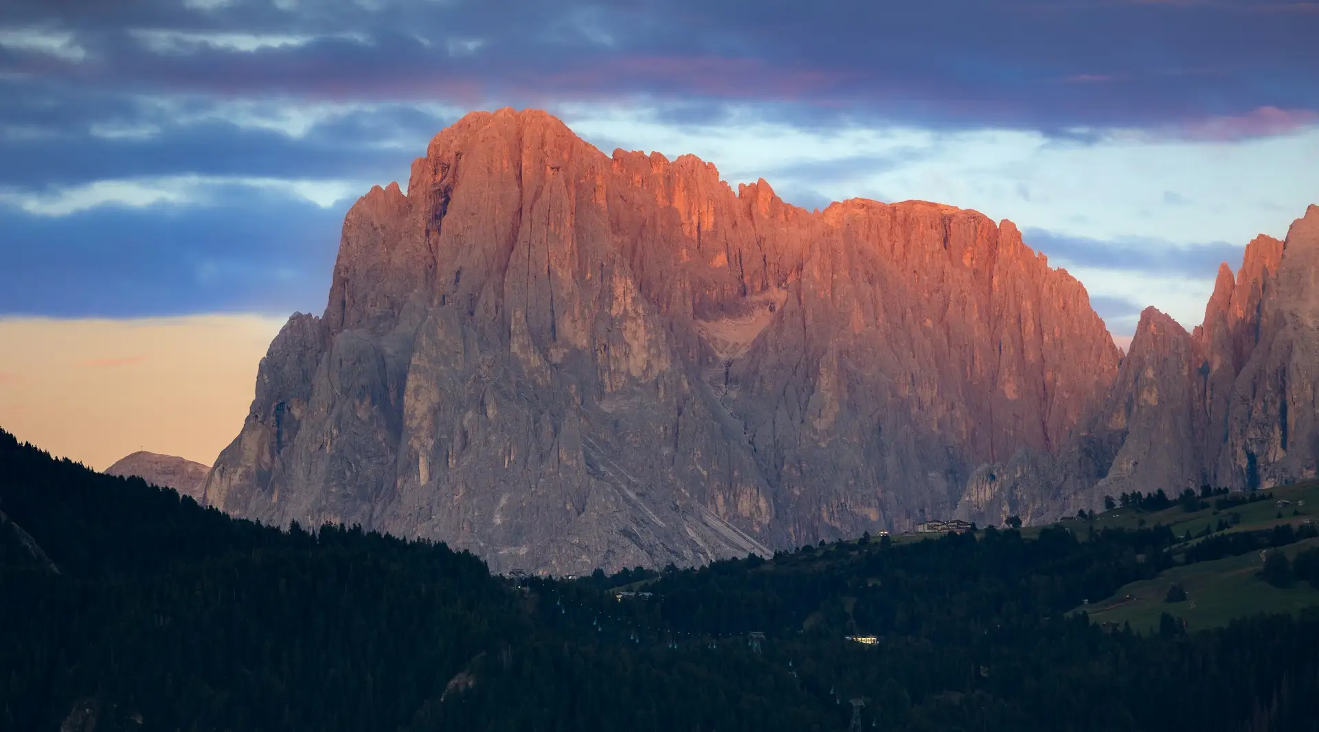 Felsgipfel im rosa Abendlicht über dunklem Wald